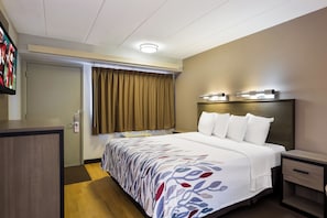 A hotel room with a bed, bedside tables, a desk, a television, and a window with curtains. - Red Roof Inn Wilkes-Barre Arena (Wilkes-Barre)