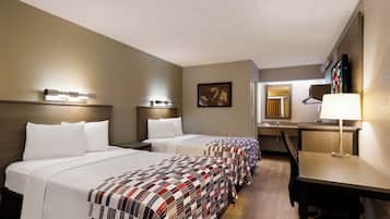 A hotel room with two beds, a desk, and a chair.