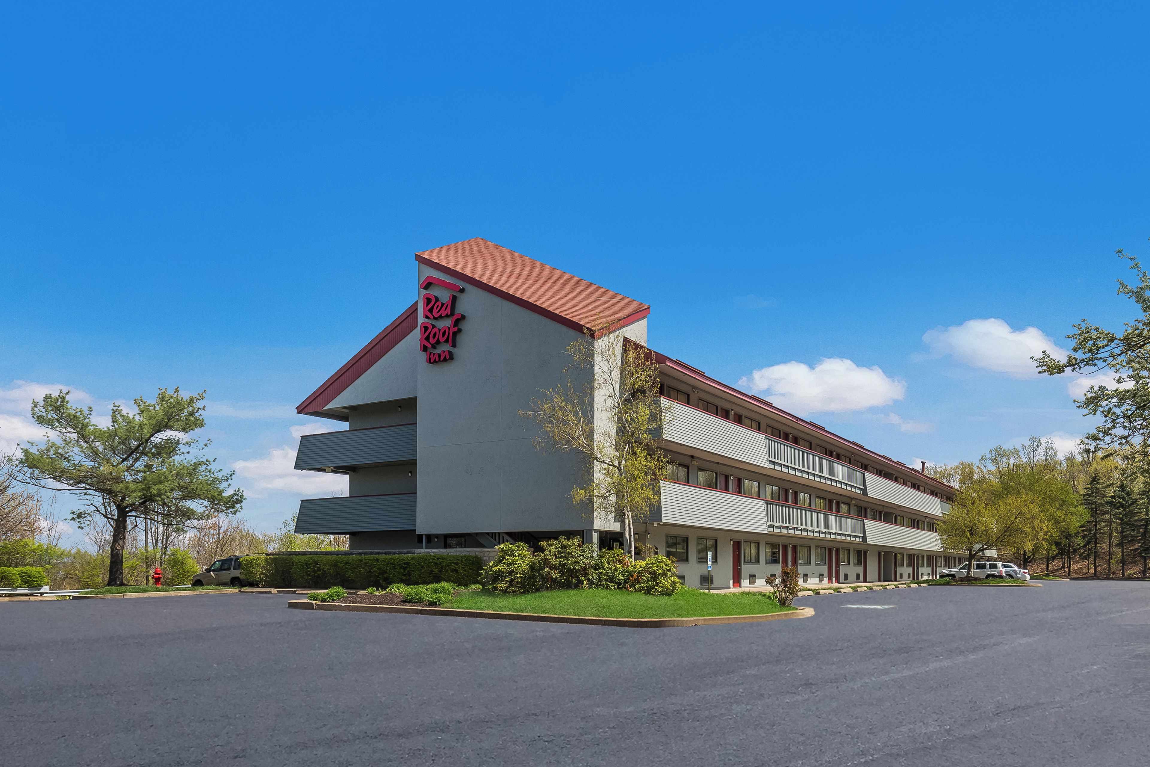 A motel with a red roof and multiple floors.