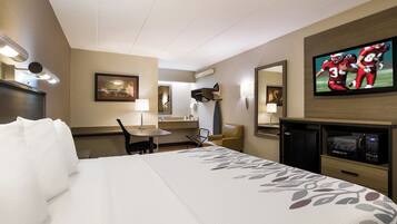 A hotel room with a bed, a desk, a chair, a television, and a microwave.