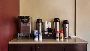 Una estación de café con cafetera, tazas térmicas y leche para café.