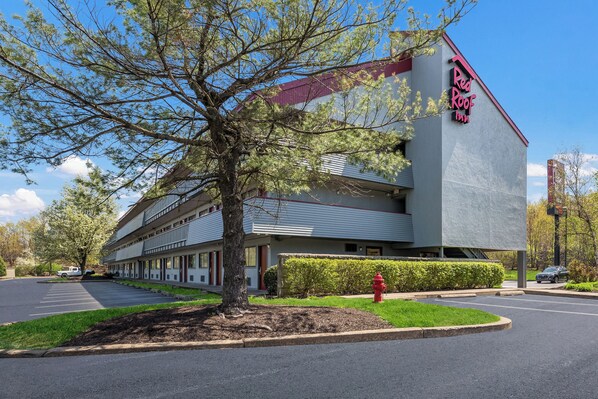 Un Red Roof Inn con diseño moderno, estacionamiento y césped bien cuidado.