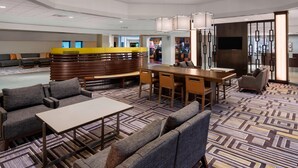 A modern hotel lobby with a central seating area, a reception desk, and a dining space. - Sheraton Harrisburg Hershey Hotel (Harrisburg)