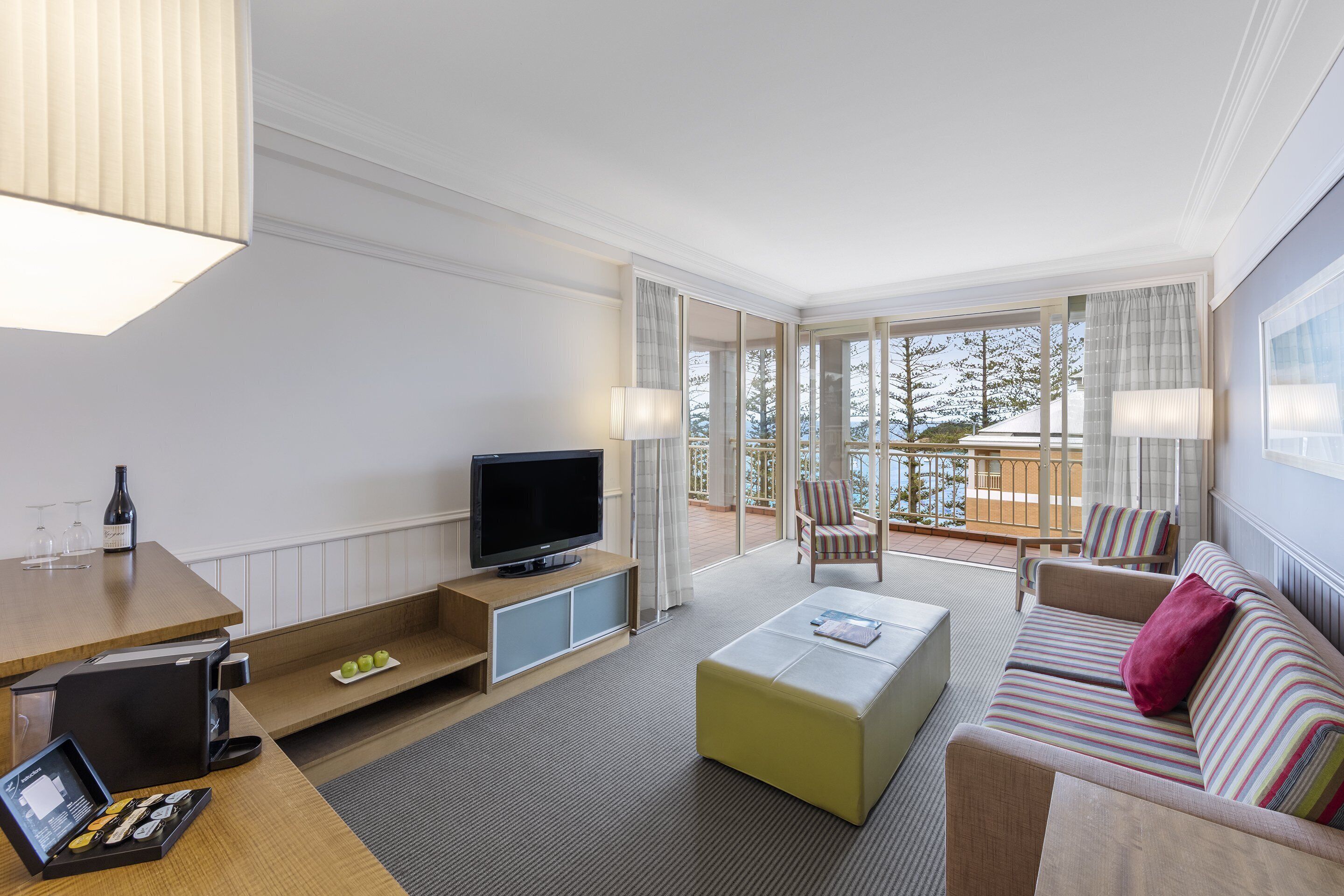 Une chambre d’hôtel moderne dotée d’une télévision, d’un coin salon et d’un balcon avec vue.