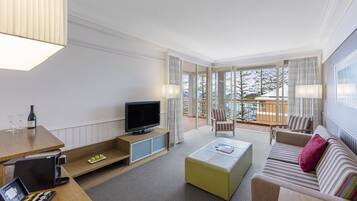 Une chambre d’hôtel moderne dotée d’une télévision, d’un coin salon et d’un balcon avec vue.