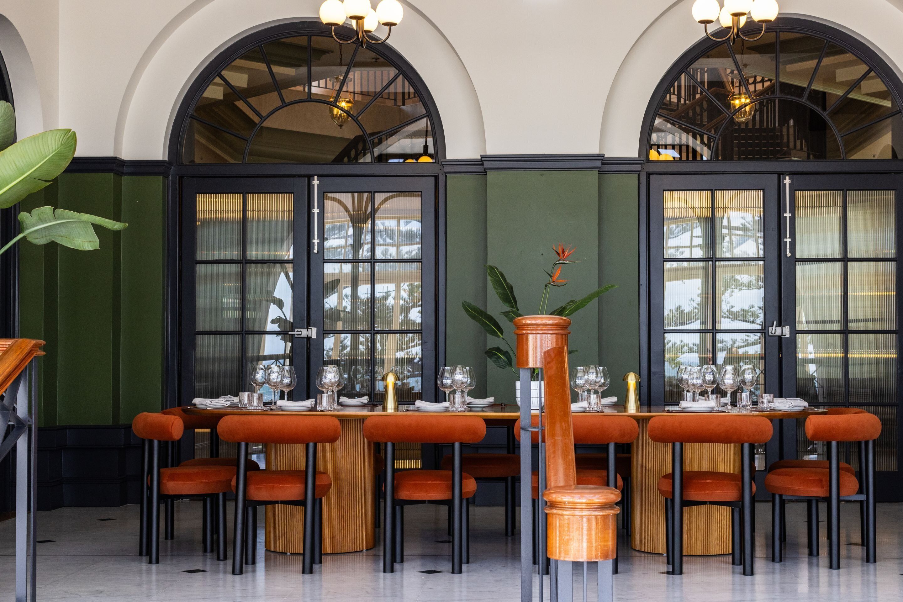 A dining area with a round table set for six, surrounded by orange upholstered chairs.