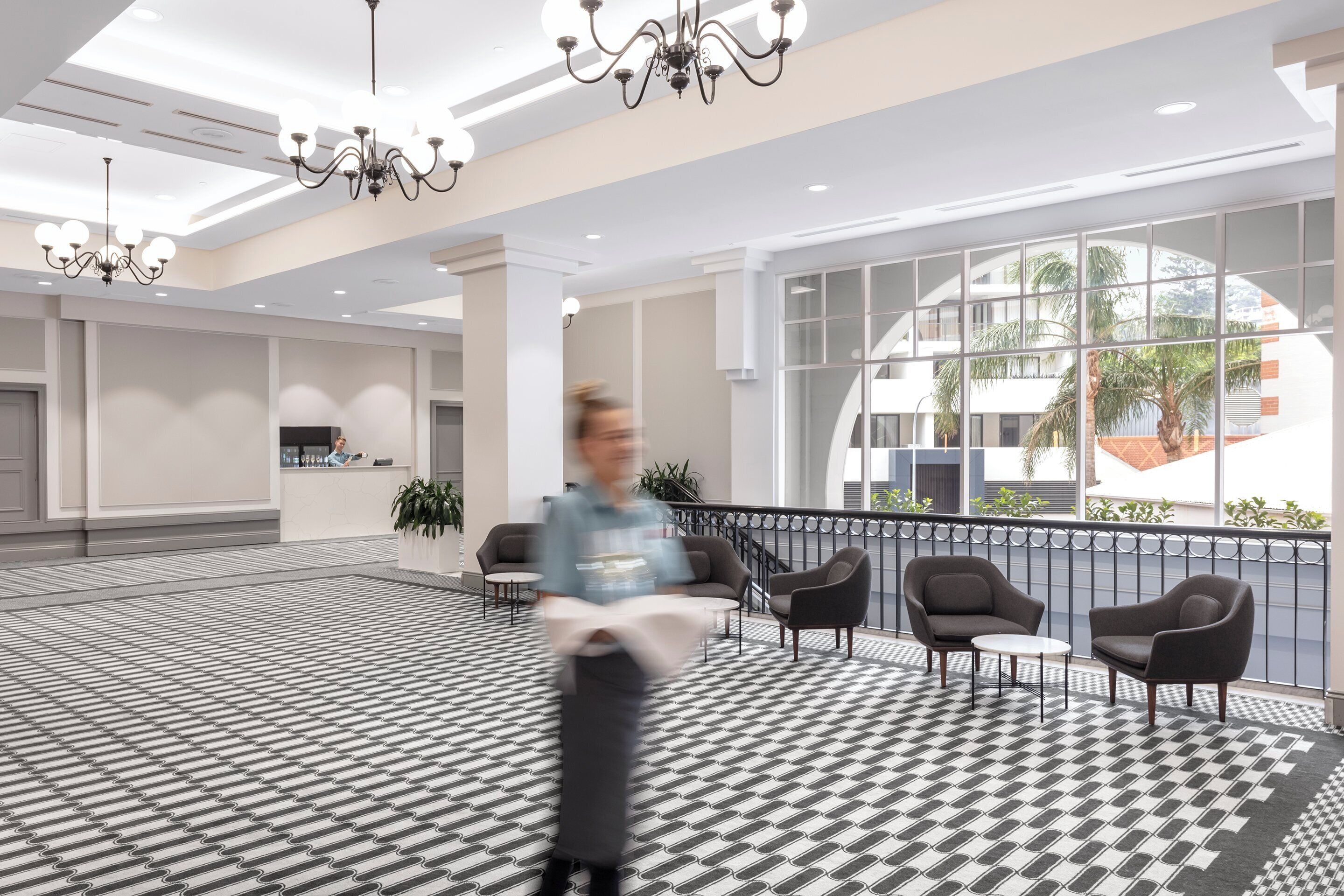 A spacious lobby with a patterned floor, modern furniture, and large windows offering views of the outdoors.