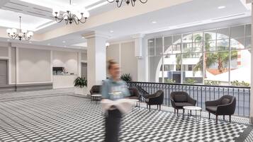 Een ruime lobby met een patroon vloer, moderne meubels en grote ramen met uitzicht op de omgeving.