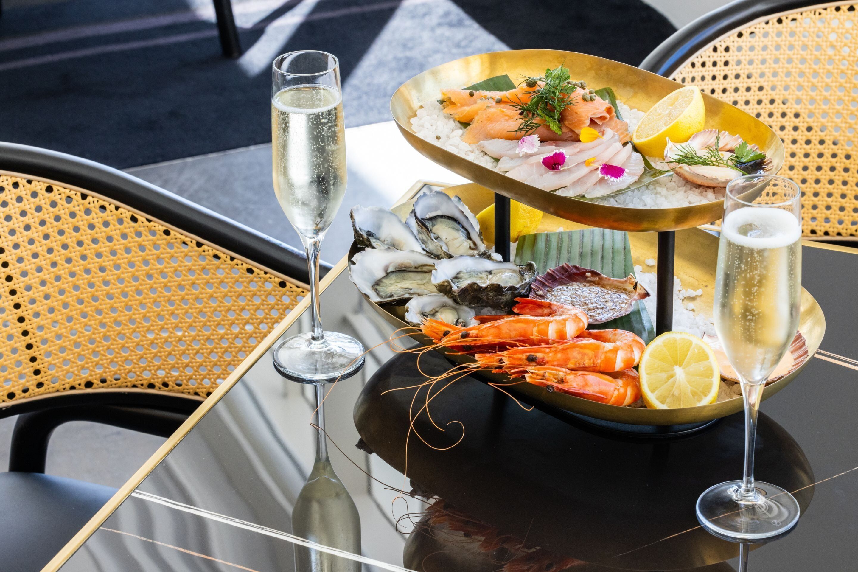 Una mesa con mariscos, una copa de champán y una botella de champán.