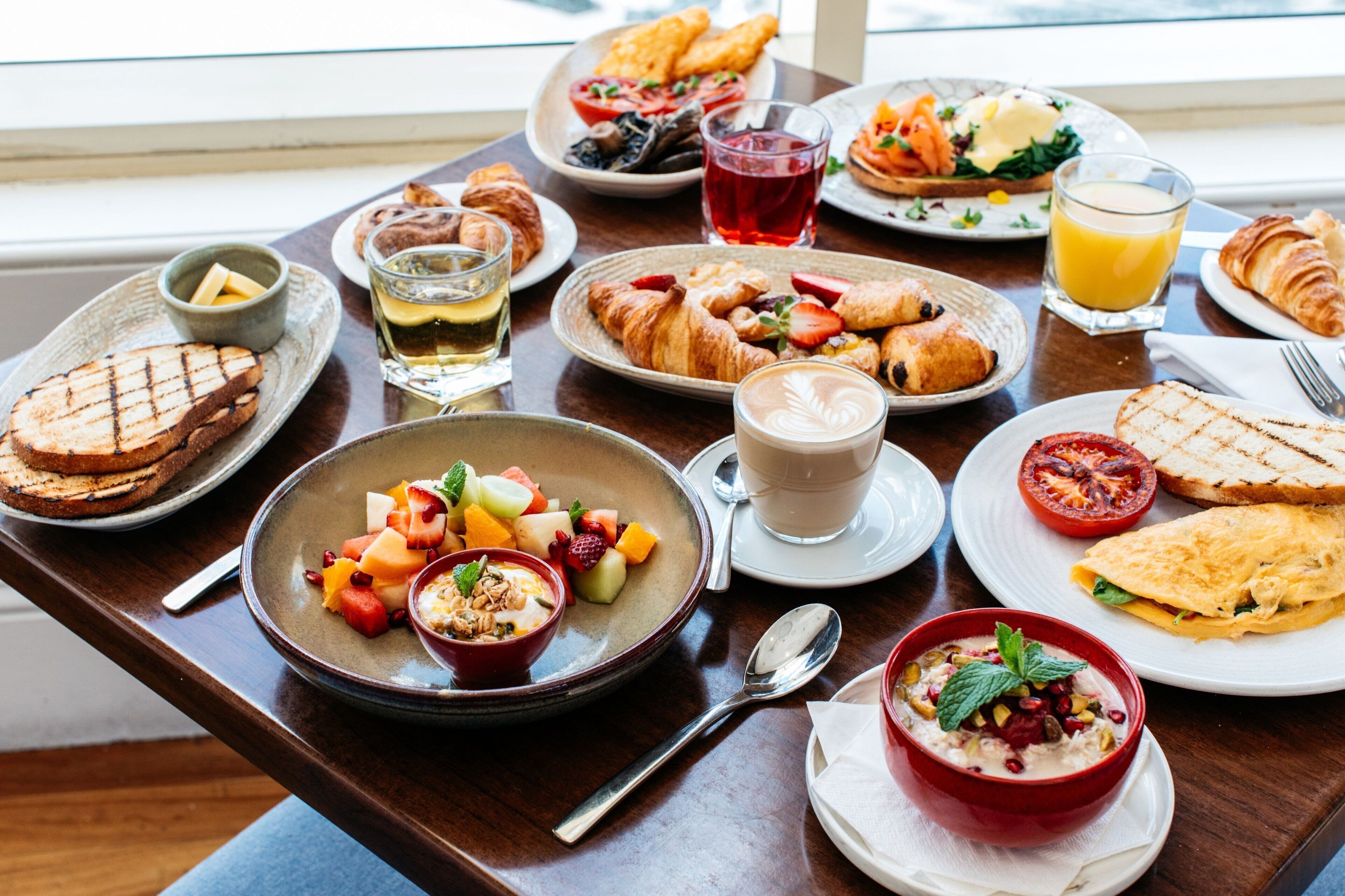 A breakfast buffet with various dishes, including croissants, fruit, and beverages.
