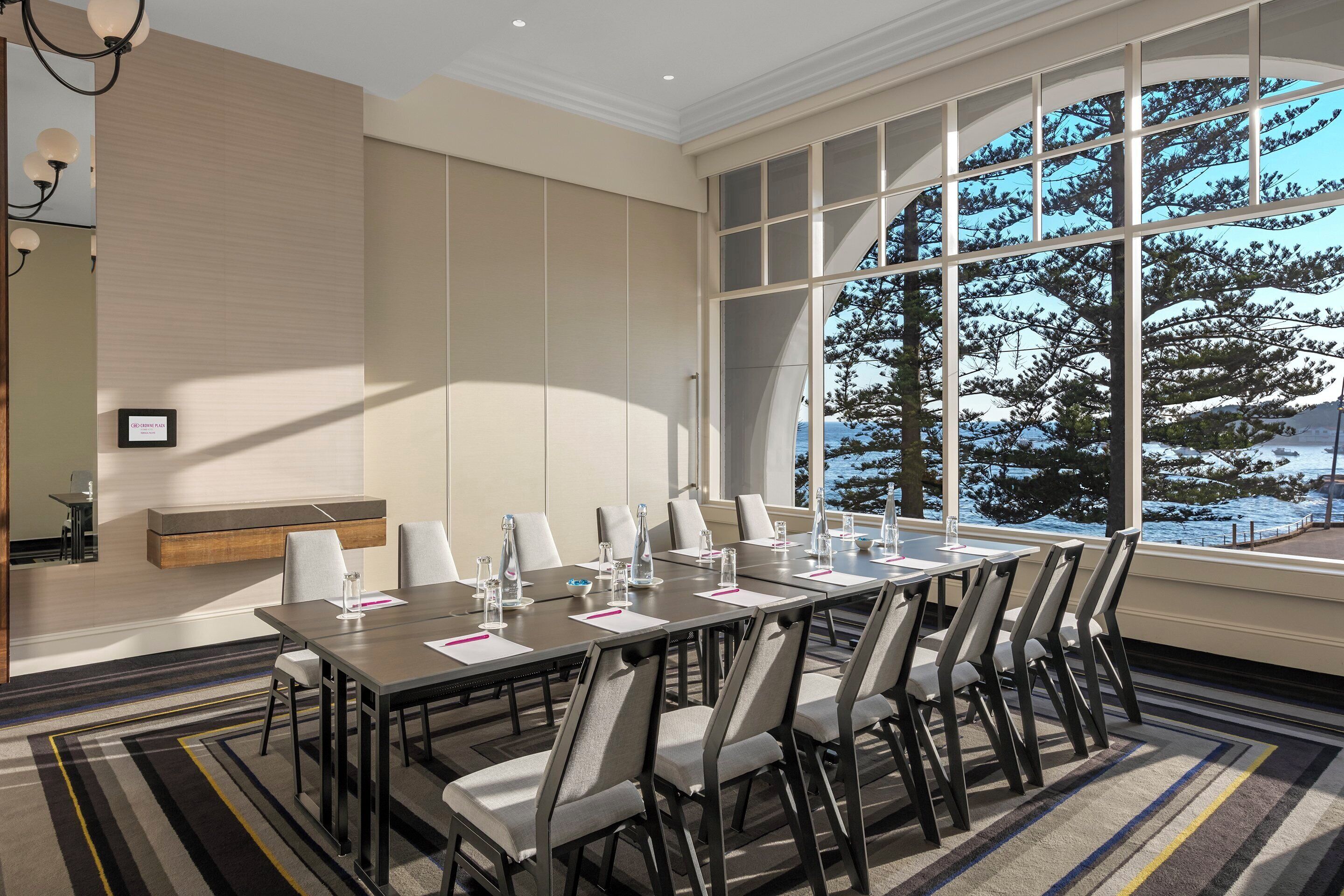 A conference room with a large table, chairs, and a view of a snowy landscape through large windows.