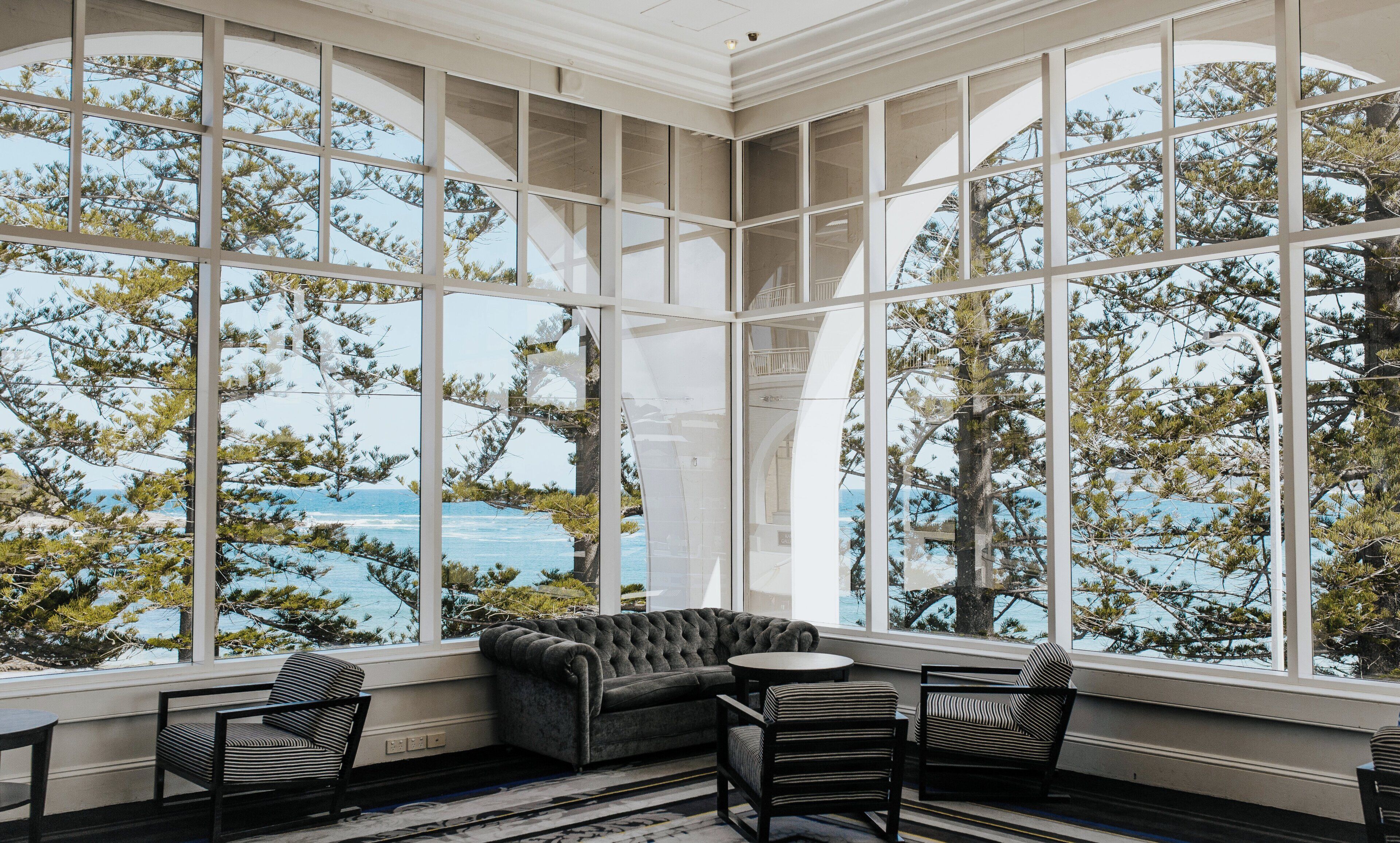 A room with large windows, a sofa, and two chairs.