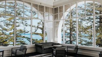 A room with large windows, a sofa, and two chairs.
