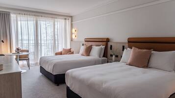 A hotel room with two beds, a desk, and a chair.