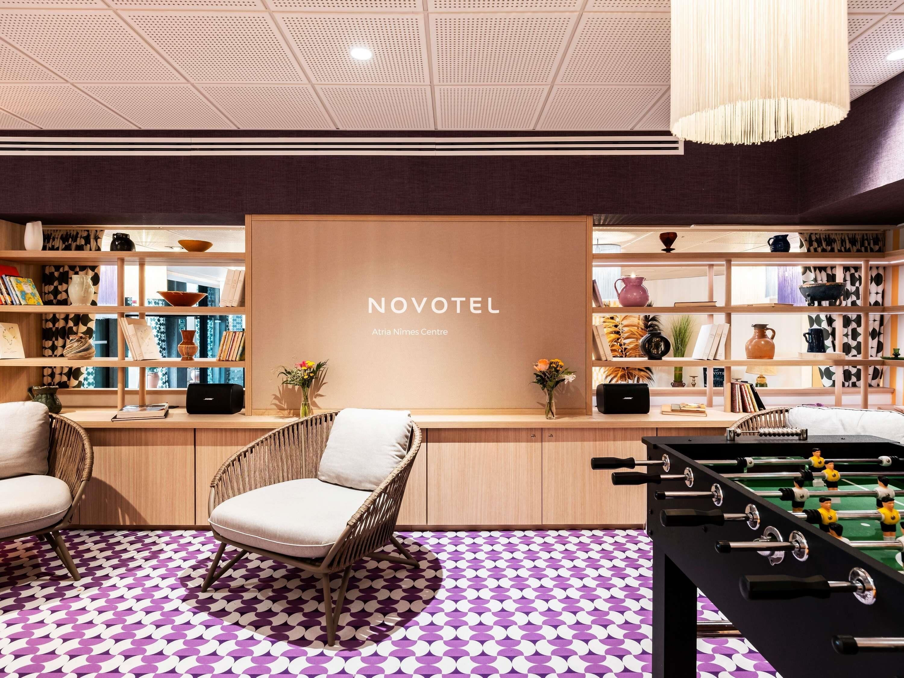 Vestíbulo del Novotel Atria Nimes Centre con una mesa de fútbol de mesa, sillas de mimbre y un piso con estampado.