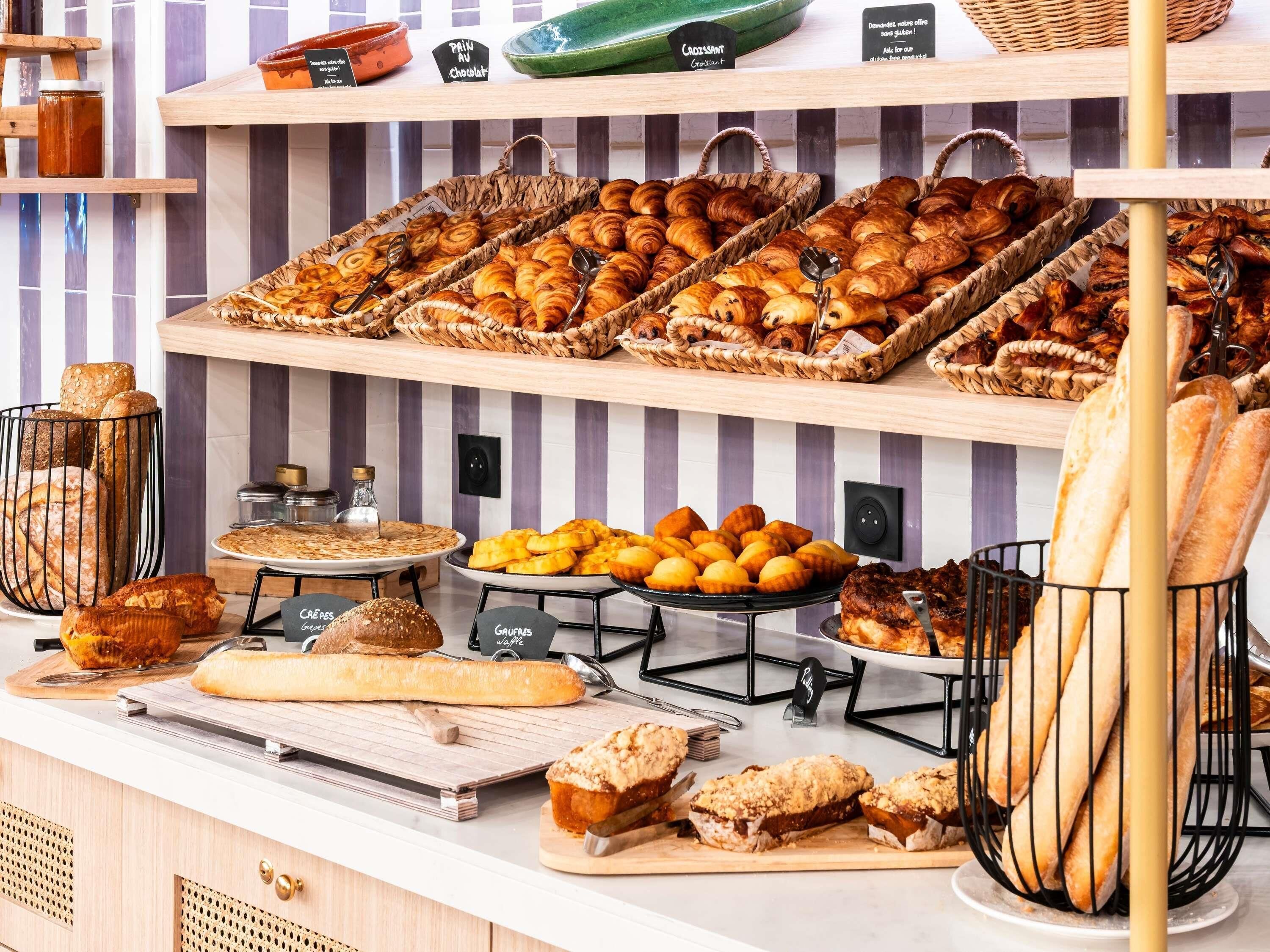 Een bakkerijvitrine met verschillende gebakjes zoals croissants, brood en muffins.