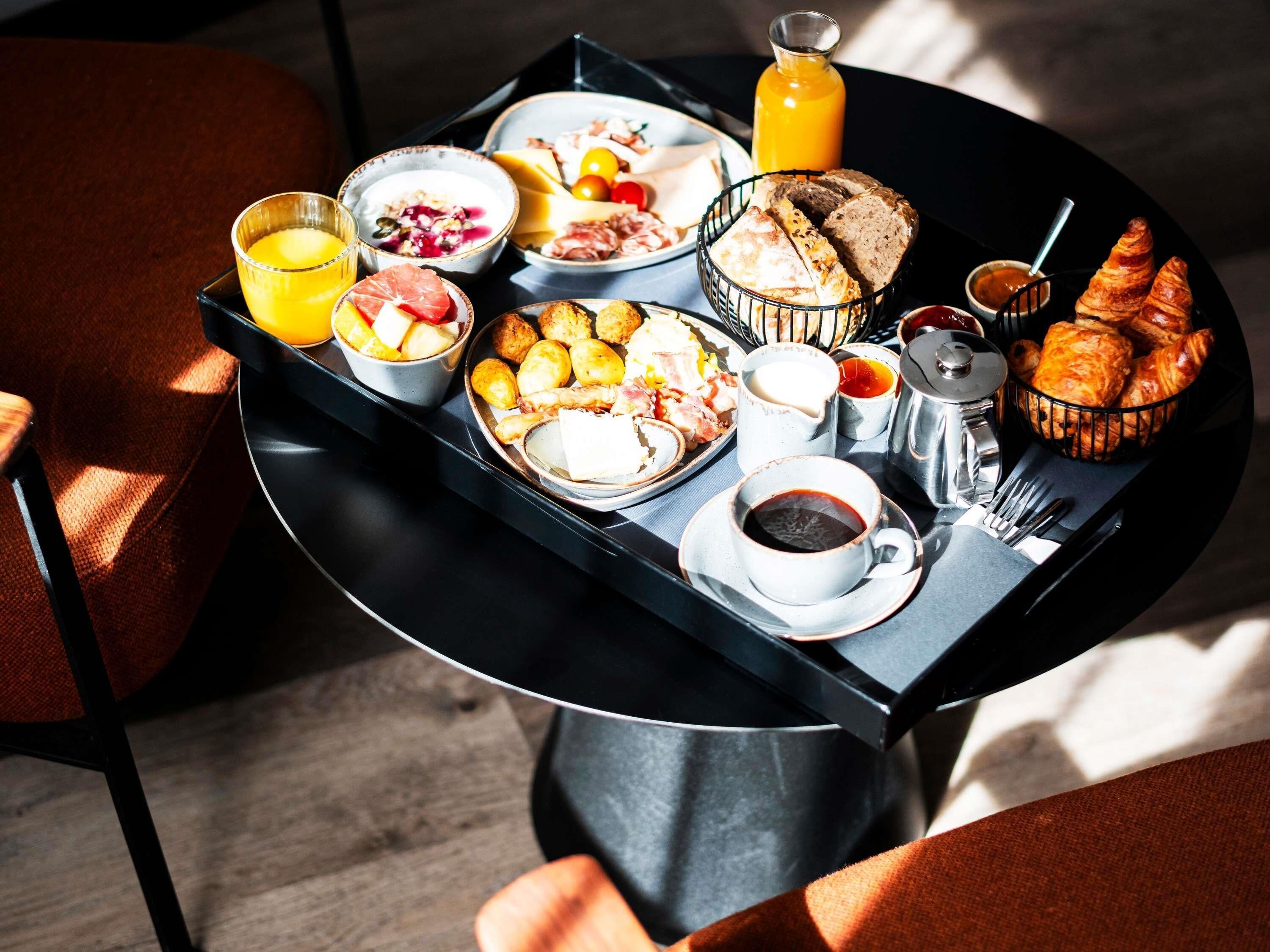 A breakfast tray with various foods and drinks, including bread, eggs, and a bottle of orange juice.