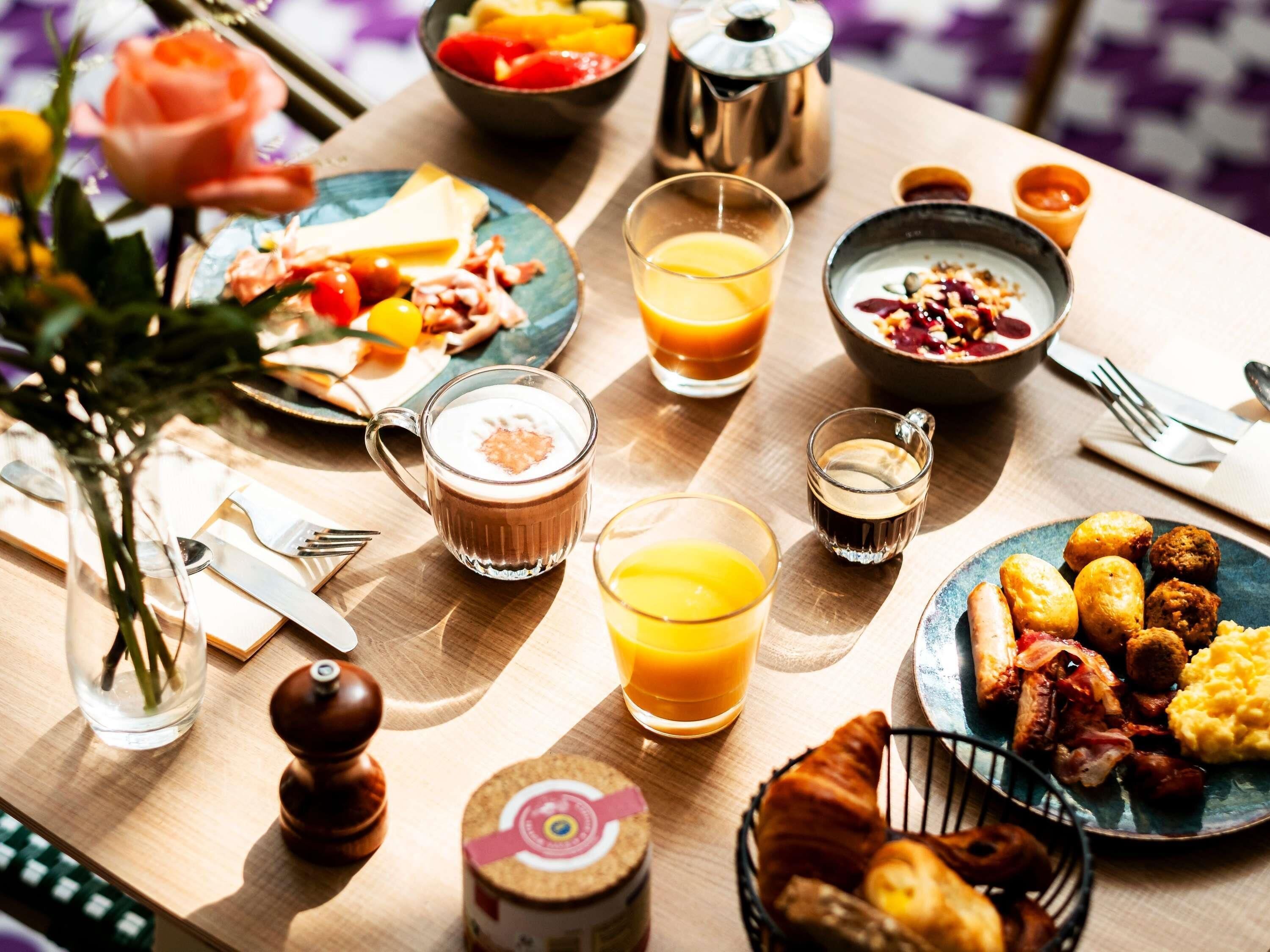 A breakfast setting with a variety of food items, including eggs, bacon, and pastries, along with beverages like orange juice and coffee.