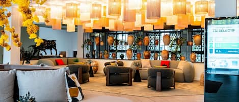 A modern lobby with a seating area, hanging lamps, and a display of pottery.