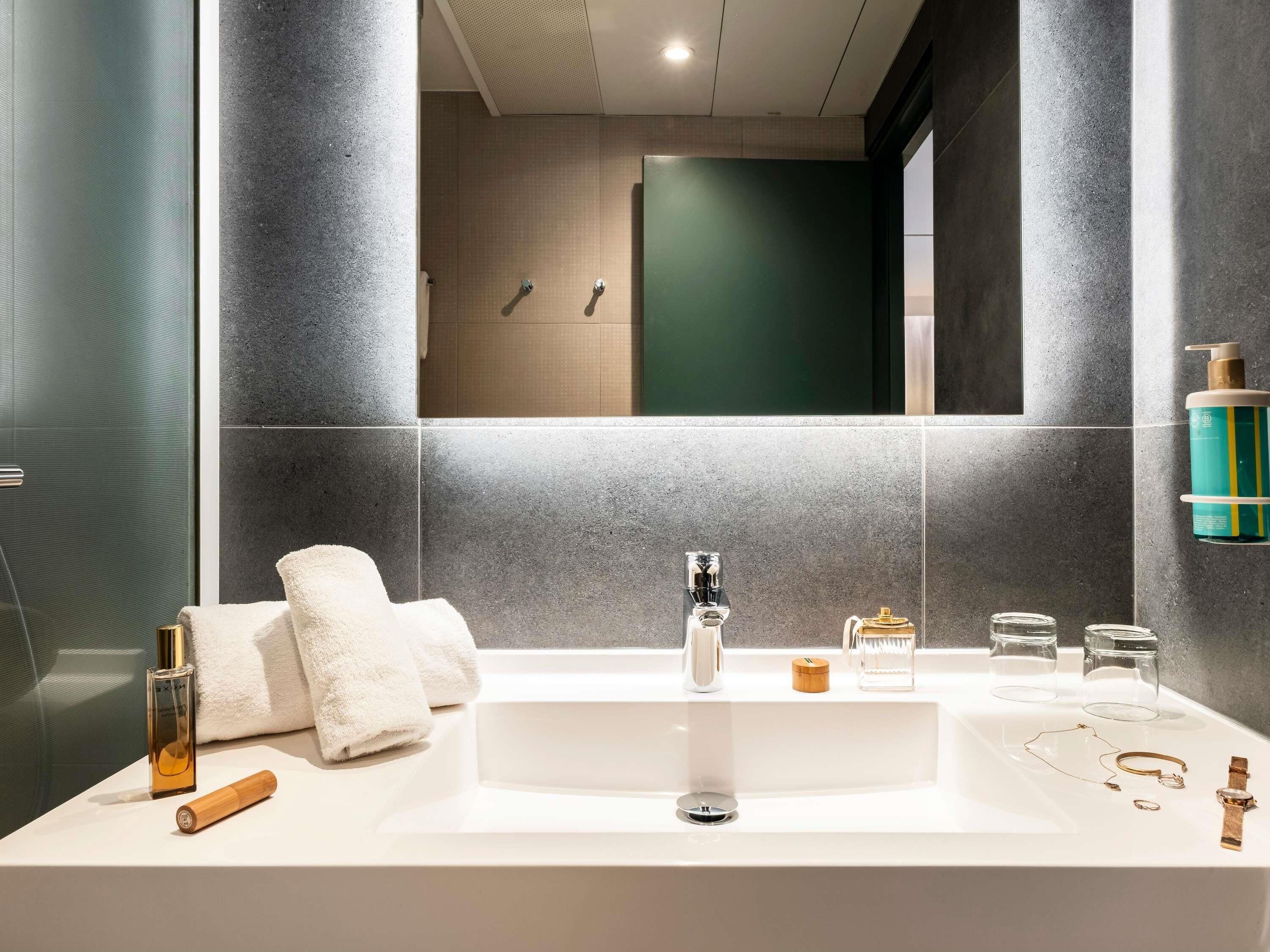 A modern bathroom with a large sink, a mirror, and a shower area.