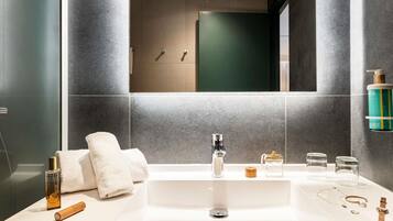 A modern bathroom with a large sink, a mirror, and a shower area.