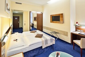 Une chambre d’hôtel avec un grand lit, un bureau, une chaise, une télévision et un miroir.