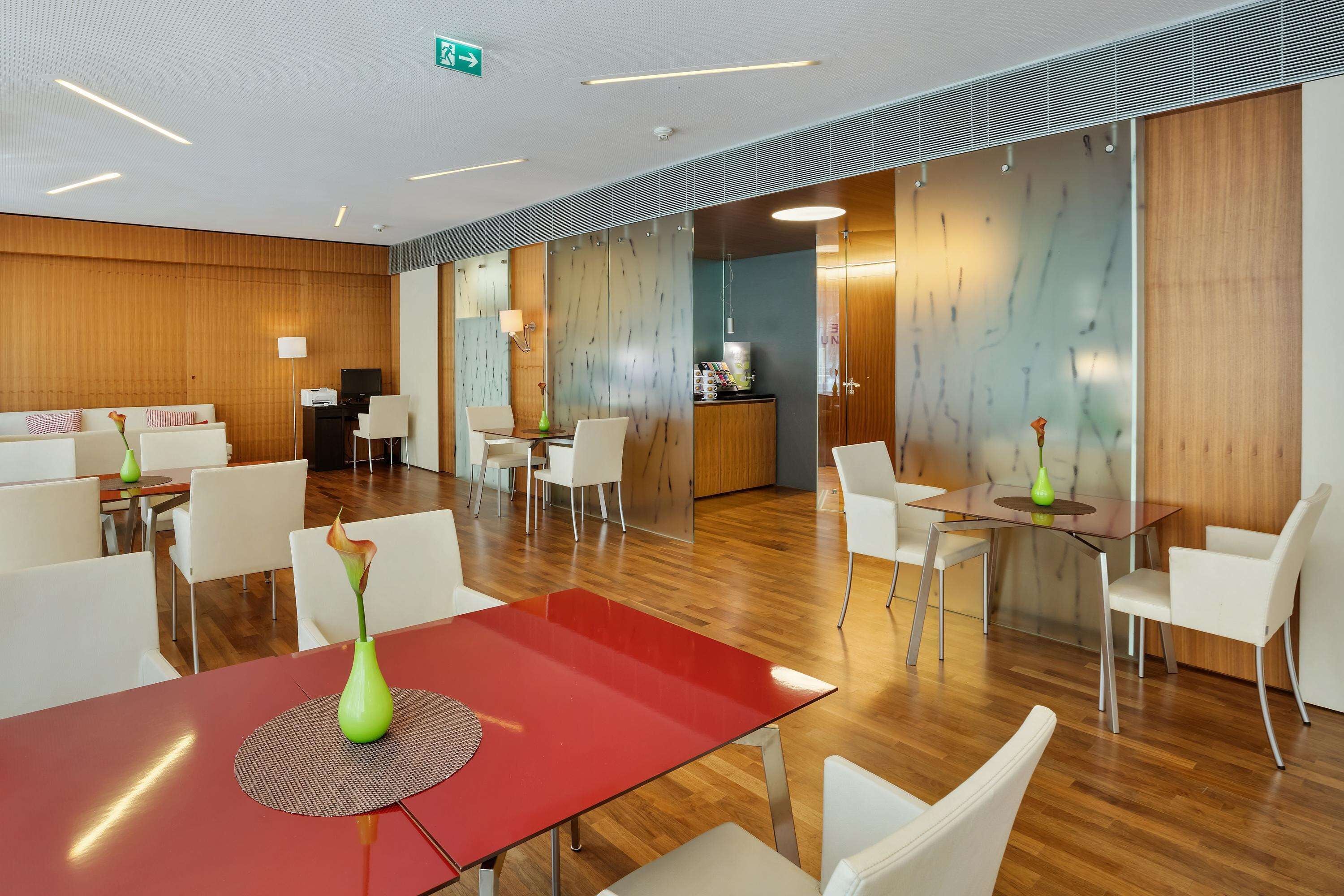 A modern hotel lobby with a red table, white chairs, and a reception area.