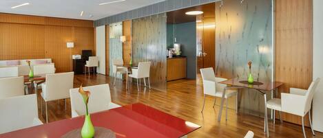 A modern hotel lobby with a red table, white chairs, and a reception area.