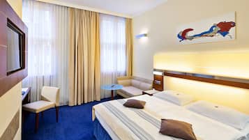 Ein Hotelzimmer mit einem großen Bett, einem Schlafsofa, einem kleinen Tisch und einem Fernseher.