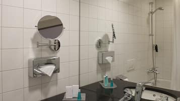 Uma casa de banho moderna com um espelho grande, uma pia e um chuveiro.