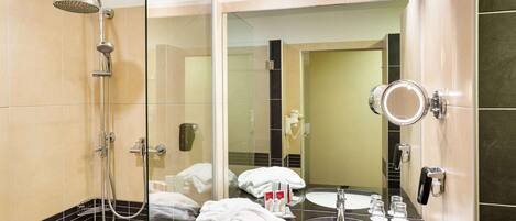 A modern bathroom with a glass-enclosed shower, a vanity with a sink, and a large mirror.