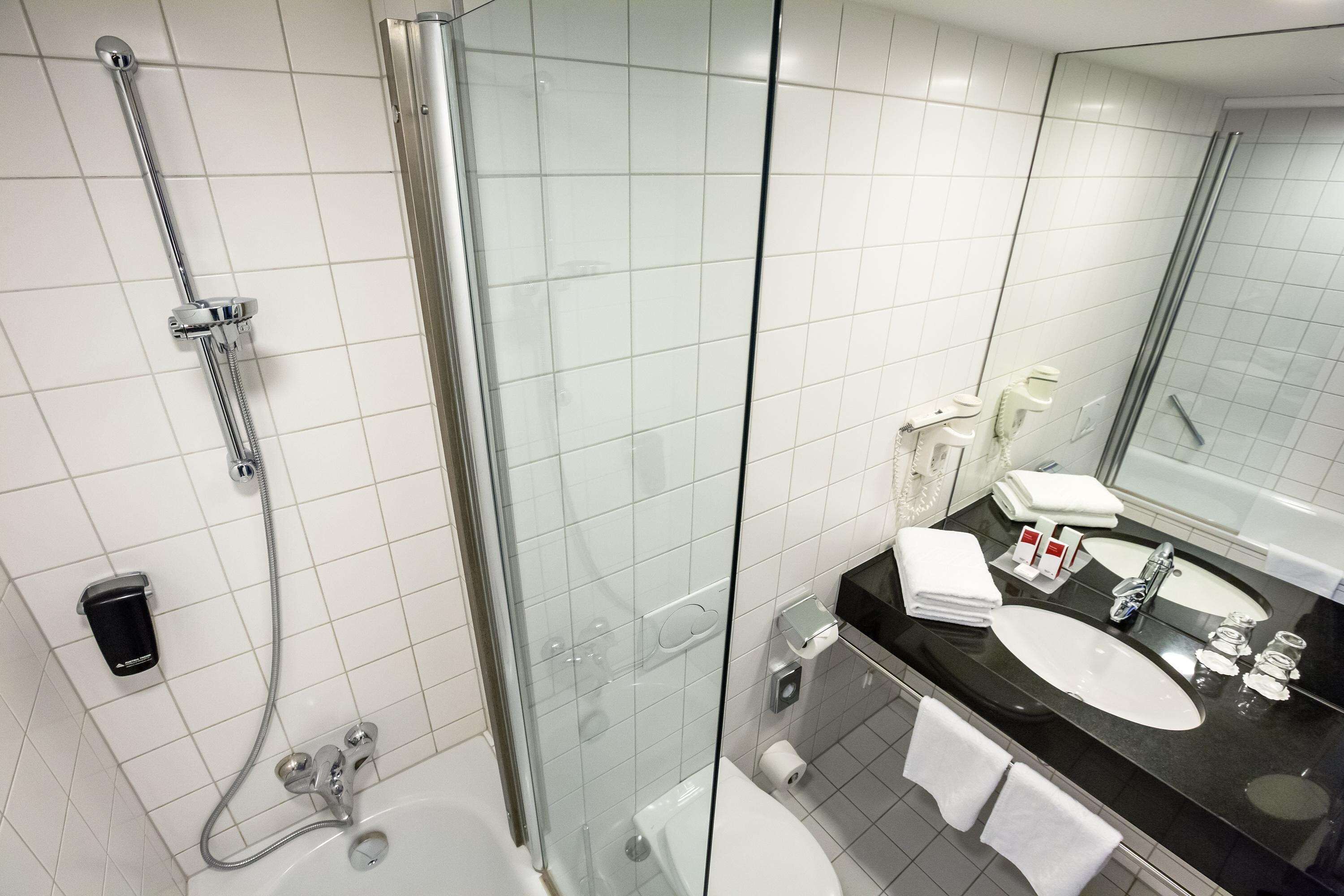 Ein modernes Badezimmer mit einer Duschkabine aus Glas, einem schwarzen Waschbecken und einem Spiegel.
