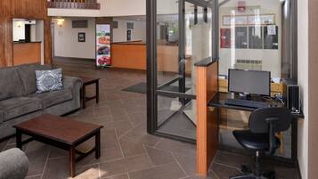 A lobby with a reception desk, a sofa, a coffee table, and a computer desk with a chair.