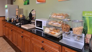 A breakfast bar with various food items, a microwave, and a coffee machine. - Quality Inn & Suites Matteson near I-57 (Matteson)