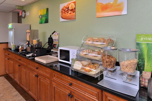 A breakfast bar with various food items, a microwave, and a coffee machine. - Quality Inn & Suites Matteson near I-57 (Matteson)