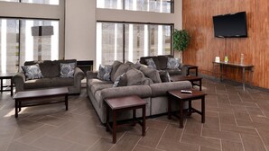 A spacious lounge area with two sofas, a coffee table, and a TV mounted on the wall. - Quality Inn & Suites Matteson near I-57 (Matteson)