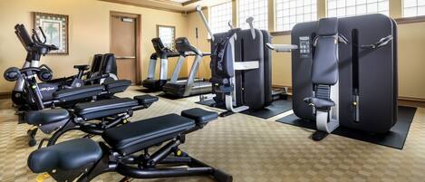 Une salle de sport équipée de divers appareils d’exercice, notamment des tapis de course, des vélos elliptiques et des bancs de musculation.