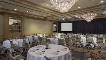 Une salle de conférence équipée de plusieurs tables rondes, de chaises et d’un grand écran.