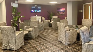 A waiting area with plaid-patterned chairs, a flat-screen TV, and a fireplace.