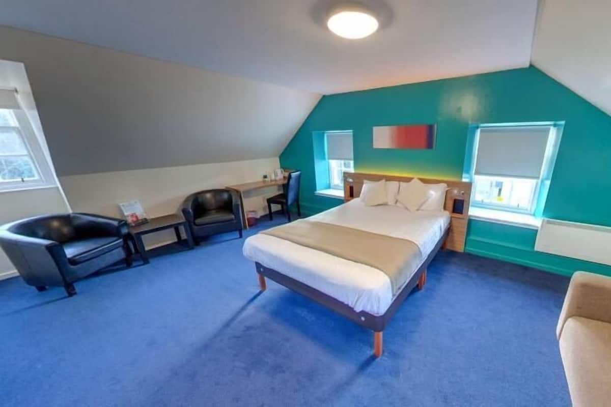 A room with a bed, a desk, a chair, and a couch.