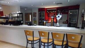 A bar area with a counter, bar stools, and a refrigerator stocked with beverages.