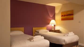 Une chambre d’hôtel avec deux lits, une table de chevet avec une lampe et un tableau au mur.