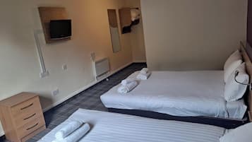 A hotel room with two beds, a TV, a heater, and a wooden dresser.