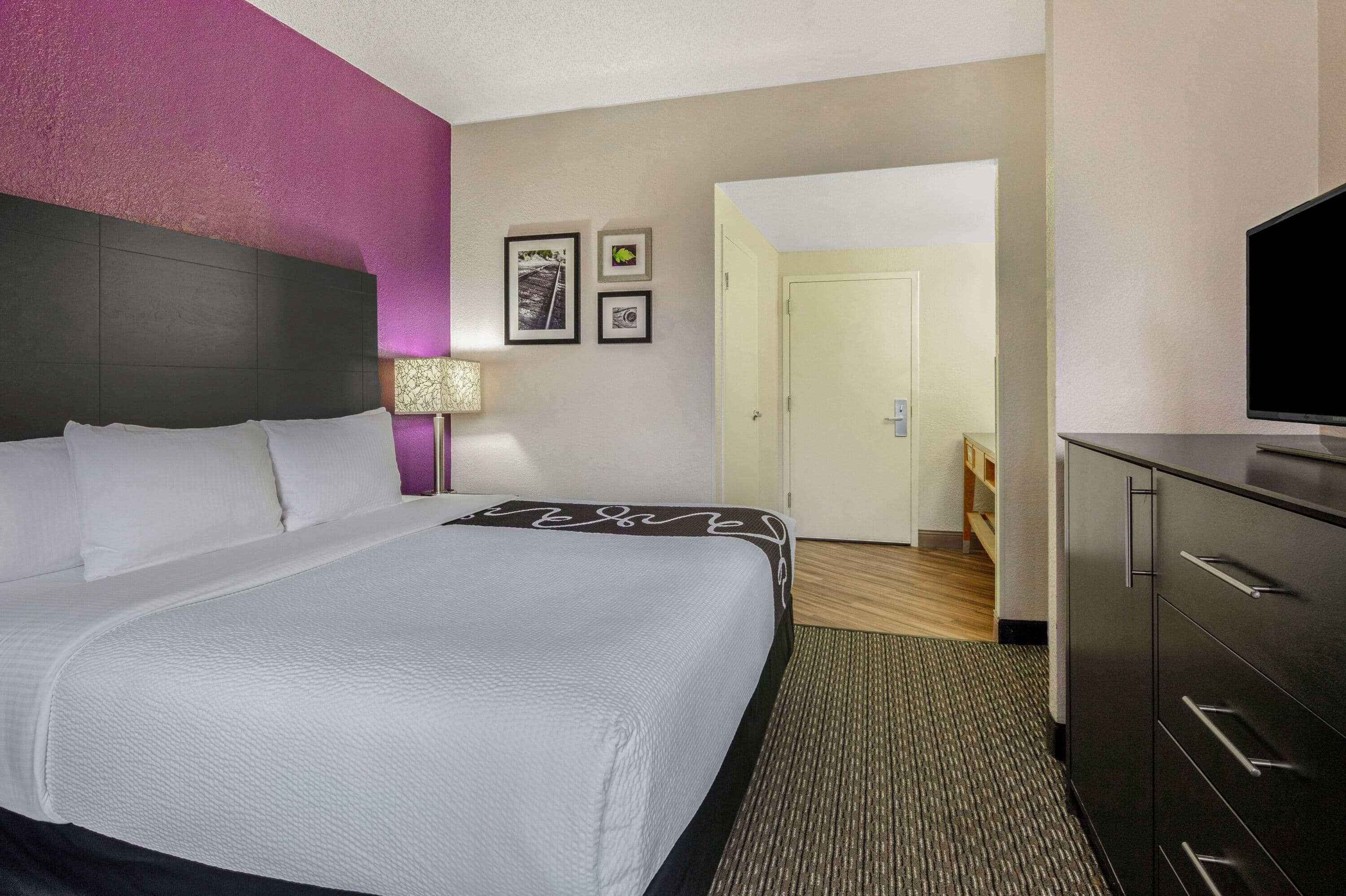 Une chambre d’hôtel avec un grand lit, un bureau, une télévision et une porte donnant sur une salle de bain.