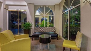 A lobby with a sofa, a round table, and a bench. - La Quinta Inn & Suites by Wyndham Miami Lakes (Miami Lakes)