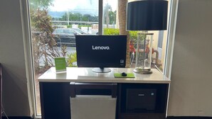 A Lenovo computer on a desk with a lamp, a chair, and a Samsung printer. - La Quinta Inn & Suites by Wyndham Miami Lakes (Miami Lakes)