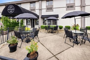 Eine Terrassengaststätte mit Tischen, Stühlen, Sonnenschirmen und Topfpflanzen.