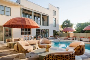 Una piscina al aire libre, sombrillas, sillones reclinables de piscina