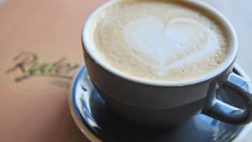 A cup of coffee with a heart-shaped latte art on a saucer.