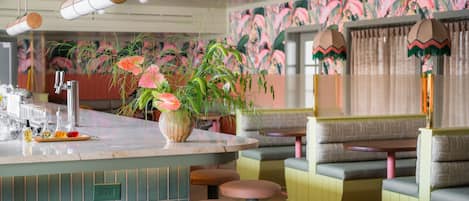 A bar area with stools, a bar counter, and a decorative plant.